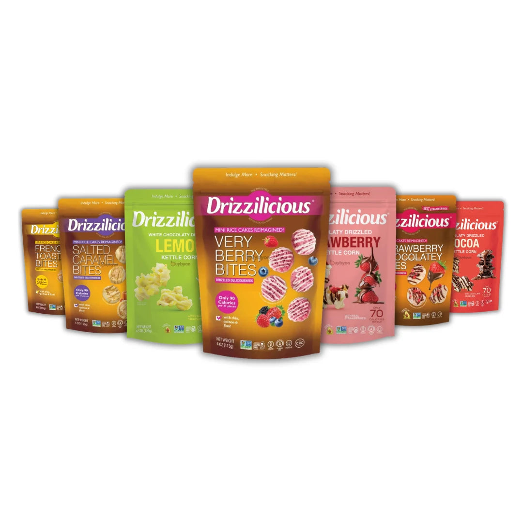Six bags of Drizzlicious snack bites arranged in a row against a white background, including Lemon Butter, Very Berry Bites, Strawberry Creamery, and Oreo flavors.